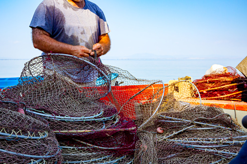 Makrygialos, Greece - August 29, 2018: Fisherman is pile up fishing net and prepare for his next angling.