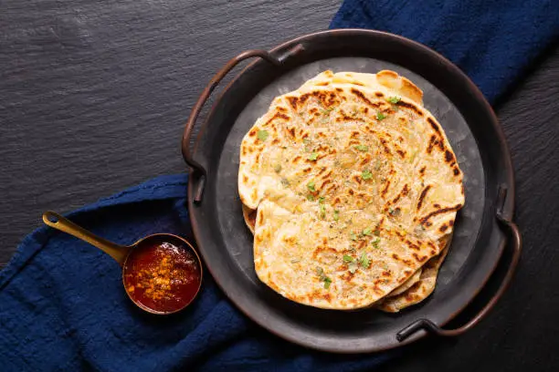 Photo of Food concept spot focus homemade Paratha, Parotta or Porotta layered flatbread  on black background with copy space
