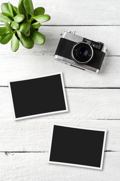 istock Empty picture frames with photo camera on white wooden table. Top view 1301576897