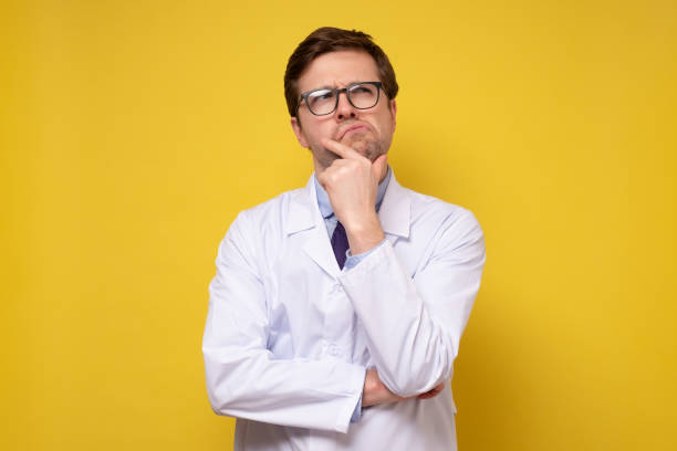 istock Puzzled young caucasian doctor thinking holding hands on chin. 1301578096