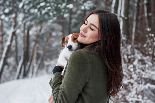 istock Satisfied look. Smiling brunette having fun while walking with her dog in the winter park 1301580273