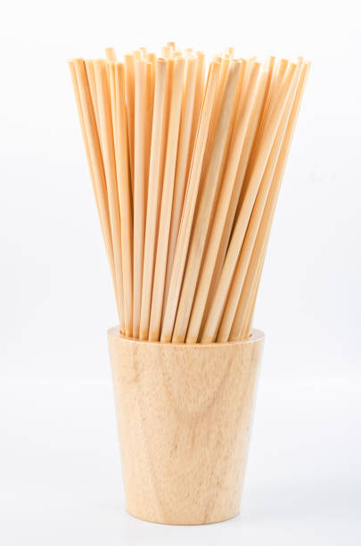 istock Wheat straw for drinking water in wooden glass on white background. 1301580521