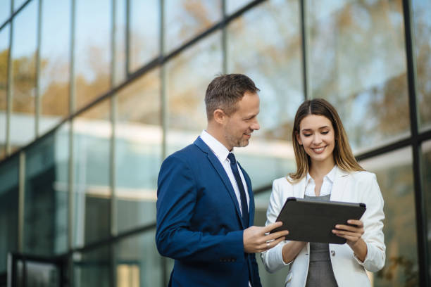 istock Two business people discussing work on tablet computer outdoors 1301583654