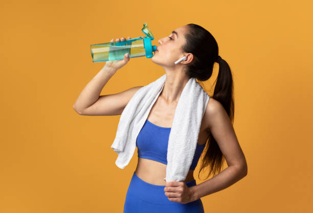 istock Sporty woman drinking water from bottle at studio 1301585984