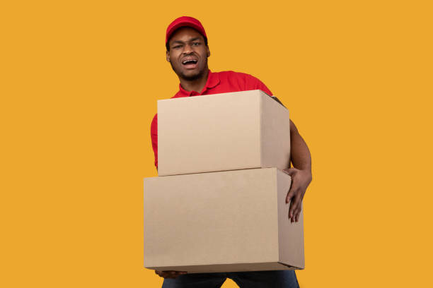 istock Black delivery man holding pile of heavy boxes 1301586775