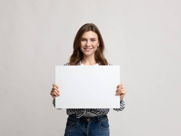 istock Beautiful Young Woman Holding Blank Placard With Copy Space For Advertisement 1301587518