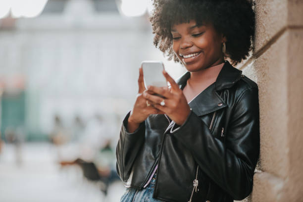 istock Smiling afro woman using phone while she is out in the city 1301588739