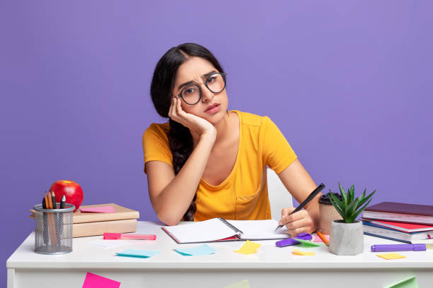 istock Tired indian woman sitting at desk writing 1301590011
