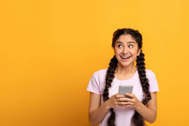 istock Indian woman using smart phone isolated on yellow background 1301590197