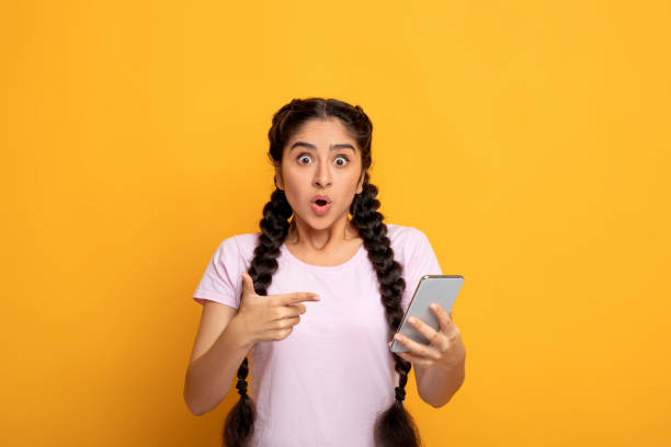 istock Excited indian woman using mobile phone, pointing at gadget 1301590255