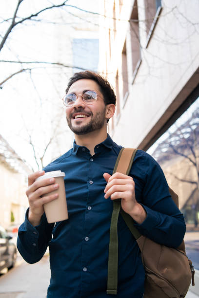 istock Young man holding a cup of coffee while walking outdoors. 1301590394