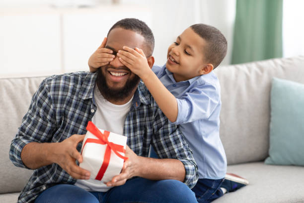 istock Little Son Congratulating Black Father Giving Wrapped Gift Indoors 1301590756