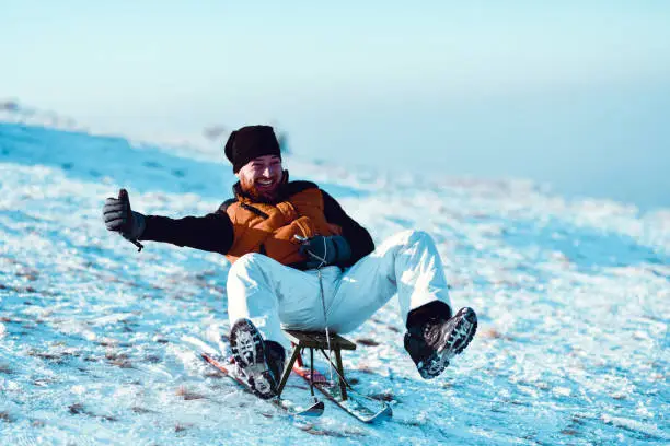 Photo of Smiling Bearded Male Speeding Downhill On His Sled