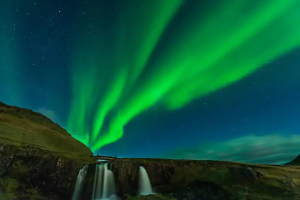 Photo of Northern lights in Iceland. Landscape full of kp5 Aurora Borealis. Amazing nightscape at Kirkjufell, scenic travel destination. Green sky full of stars