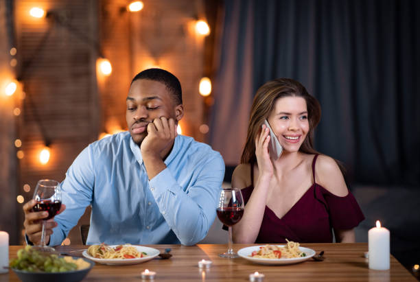 istock Black guy sitting bored while his girlfriend talking on cellphone in restaurant 1301593714