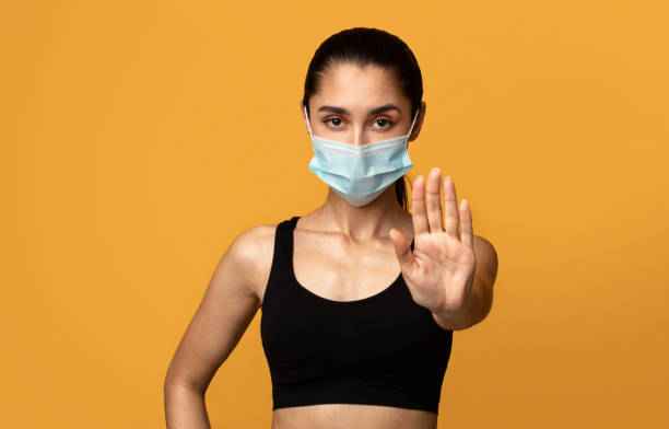 istock Woman wearing protective face mask showing stop sign 1301595829