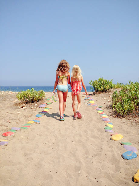 duas jovens caminhando juntos para a praia nas férias de verão - mobilestock freedom enjoyment blue - fotografias e filmes do acervo