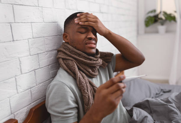 istock Guy Holding Thermometer Having Fever Sitting In Bed At Home 1301596550