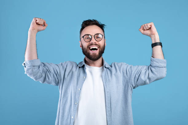 istock Overjoyed bearded guy in glasses making YES gesture with both hands on blue studio background, panorama 1301596778