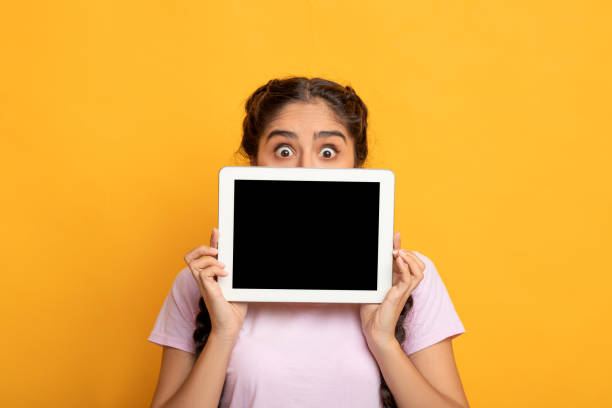 donna indiana sorpresa che mostra lo schermo del tablet vuoto - hiding internet multimedia people foto e immagini stock