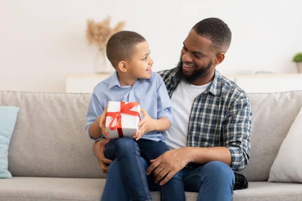 istock Black Daddy Congratulating Kid Son Giving Birthday Gift At Home 1301598095