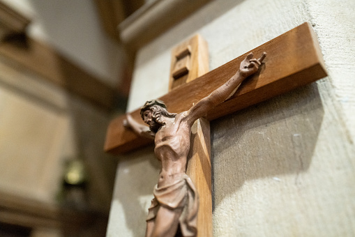 Close up color image depicting a wooden carving of Jesus on a crucfix inside an anglican church.