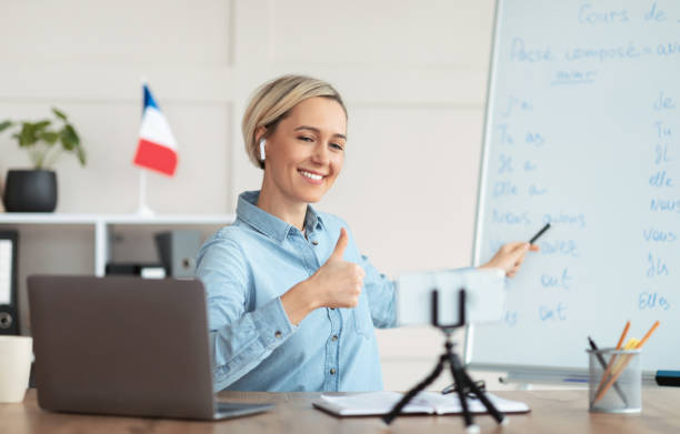 istock Online French lesson. Foreign languages tutor teaching class on webcam, talking to students, showing thumb up at home 1301600090