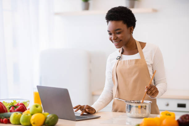 istock African Lady Cooking Using Laptop Browsing Recipes Online At Home 1301601259