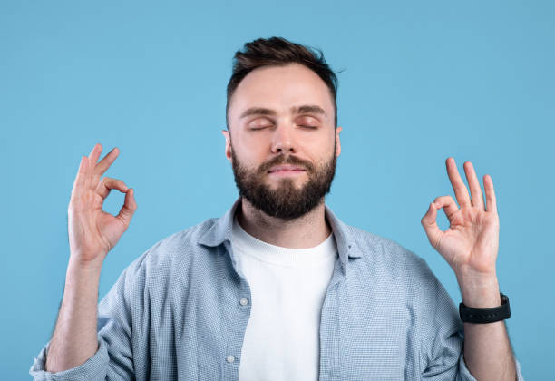 istock Calm young man meditating to relieve stress, finding inner peace and harmony on blue studio background 1301601595