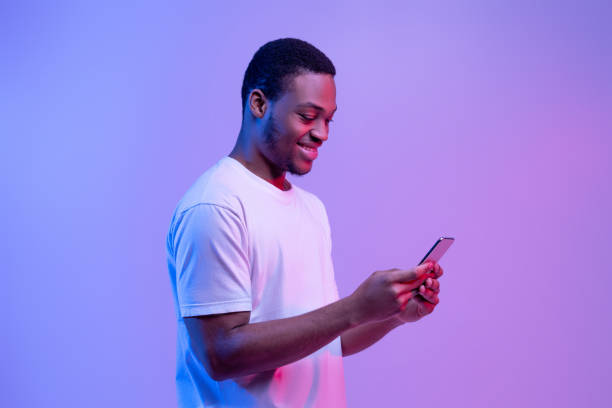 istock Messages from social network. Smiling young man look at luminous smartphone in neon light, copy space 1301602359