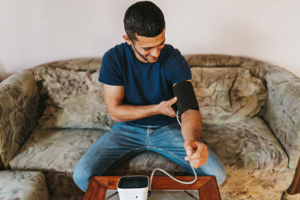 istock Handsome man sitting on sofa at home and measuring blood pressure 1301602714