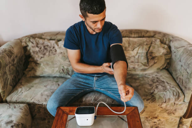istock Handsome man sitting on sofa at home and measuring blood pressure 1301602786