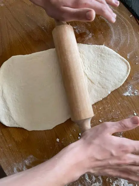 baker kneading dough with rolling pin