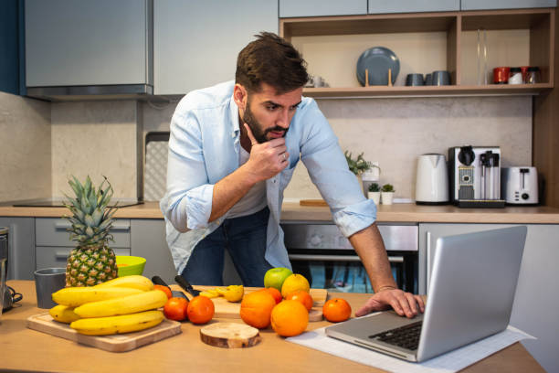 istock Handsome man cooking on kitchen and looking recipe on laptop on table 1301607959