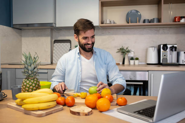 istock Handsome man cooking on kitchen and looking recipe on laptop on table 1301608050