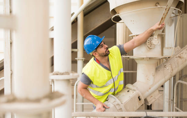 construction worker adjusts the lever to let the water pass into the giant cement mixer. Opening the stopcock stock photo