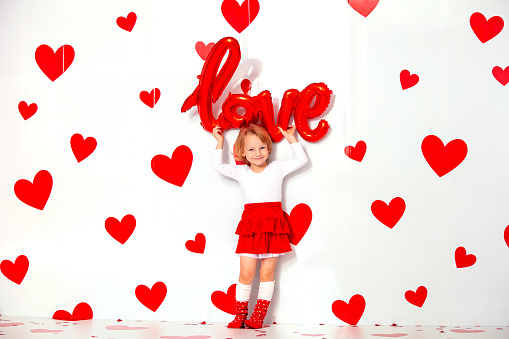 Little cute beautiful child girl with red hearts funny and happy