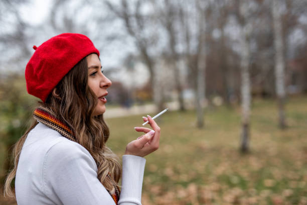 istock Young woman smoking cigarette in public park 1301612528
