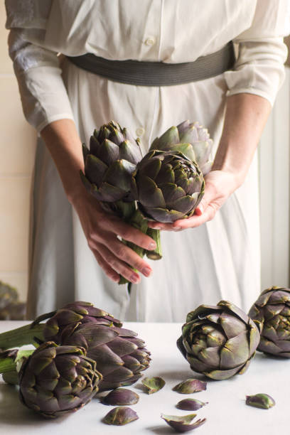 istock Woman holding fresh artichoke. Close up 1301612817