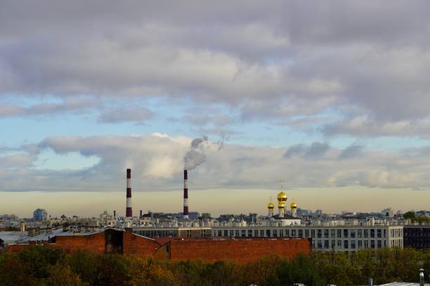An industrial urban landscape of a grass on a foreground and a steelworks with smoking pipes and a cloudy sky on the background. The photo was shot in IJmuiden city, Holland. High quality photo un paisaje urbano industrial y una acería con tuberías humeante y un cielo nublado en el fondo. contraste de paisaje urbano - la tubería de la planta y las cúpulas de la iglesia contra un hermoso cielo. la foto fue tomada en san petersburgo, rusia