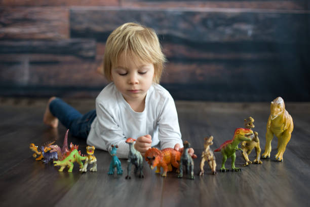 istock Blond toddler child, playing with dinosaurs at home 1301618104