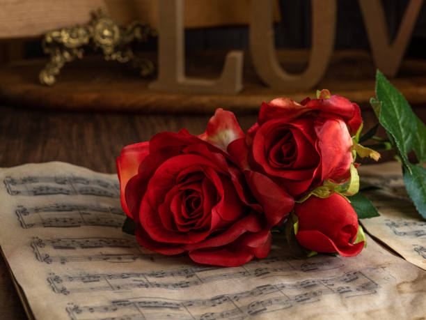 istock Valentine red roses lying on vintage music sheets. 1301618229
