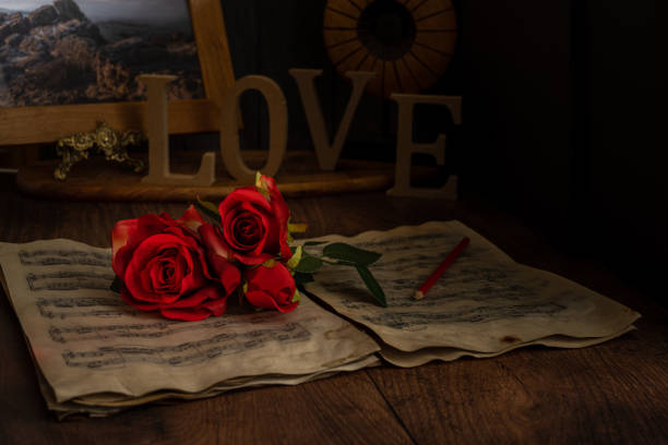 Valentine red roses lying on vintage music sheets with the word love.