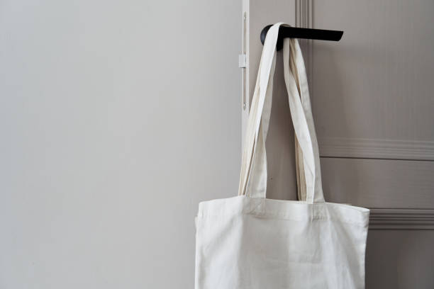 istock White eco friendly bag hanging on the door handle. Canvas tote bag 1301618594