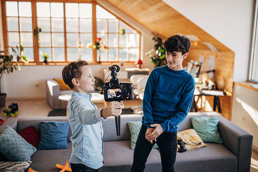 Two boys, cute modern boys making another video for their audience with camera at home.