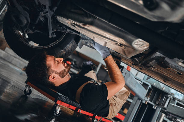 istock Mechanic in uniform lying down and working under car at auto service garage. Service and maintenance vehicle concept. 1301626845