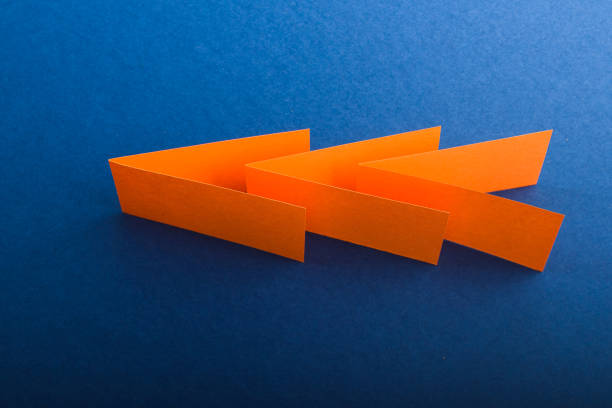 istock Multicolored cut paper on blue. Abstract arrows, direction signs. 1301628143