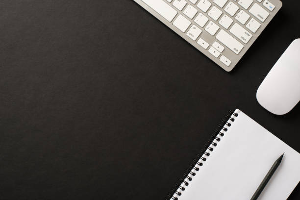istock Above overhead flatlay view photo image of computer keyboard wireless mouse spiral notebook diary organizer pencil isolated black color backdrop with space for design 1301631122