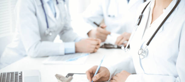 istock Group of unknown doctors discussing problems to stop coronavirus pandemic while sitting at meeting in clinic, close-up . Medicine concept 1301632317