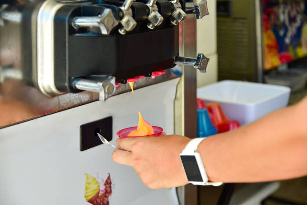 Girl hand takes ice cream into a cup from the machine Girl hand takes ice cream into a cup from the machine. ice machines stock pictures, royalty-free photos & images